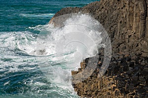 The Pacific ocean crashes into the columnar basalt rocks of Fingal Head, New South Wales