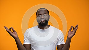Pacified black man meditating against yellow background, breathing exercises