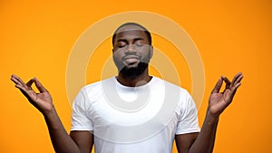 Pacified black man meditating against yellow background, breathing exercises photo