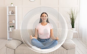 Pacified calm contented smiling millennial european woman meditating on sofa in living room interior photo