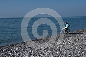 Pacified caucasian woman in a wheelchair on the seashore. photo