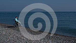 Pacified caucasian woman in a wheelchair on the seashore. photo