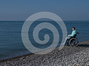 Pacified caucasian woman in a wheelchair on the seashore. photo