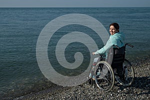 Pacified caucasian woman in a wheelchair on the seashore. photo