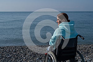 Pacified caucasian woman in a wheelchair on the seashore. photo