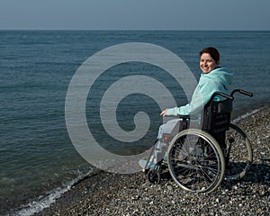 Pacified caucasian woman in a wheelchair on the seashore. photo