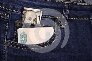 A pack of American hundred-dollar bills and Russian rubles in a pocket of blue jeans. Money in pocket cash