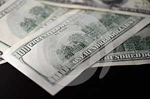 A pack of hundred dollar bills on a dark background