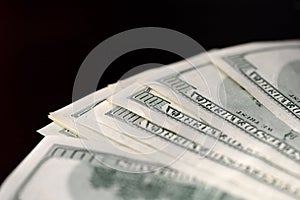 A pack of hundred dollar bills on a dark background