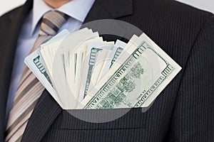 Pack of hundred dollars bills in pocket of suit of businessman in shirt and tie. Successful investor making money in global
