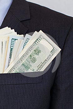 Pack of hundred dollars bills in pocket of suit of businessman in shirt and tie. Successful investor making money in global