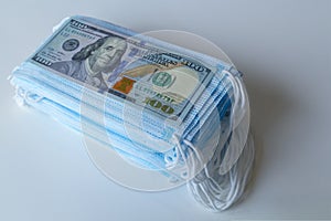 A pack of medical masks and a 100 dollars bills as a symbol of higher prices and a deficiency in the protection of the respiratory