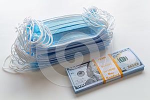 A pack of medical masks and a stack of 100 dollars bills as a symbol of higher prices and a deficiency in the protection of the