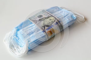 A pack of medical masks wrapped a 100 dollars bills as a symbol of higher prices and a deficiency in the protection of the