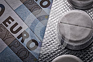 Pack of medicine pills on 20 euro banknotes macro image