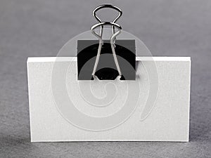 Pack of paper blanks for business cards with a metal clip on a light background