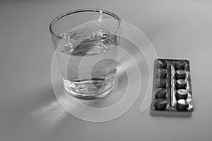 Pack of pills and glass of water. Black and White