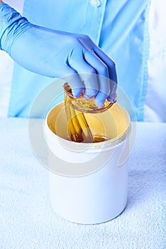 A pack of stretchy golden luminous sugaring paste with a hand taking it