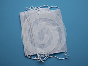 Pack of white surgical masks on a blue background top view