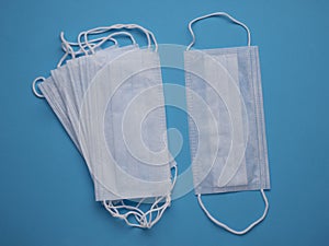 Pack of white surgical masks on a blue background top view and one mask lies separately