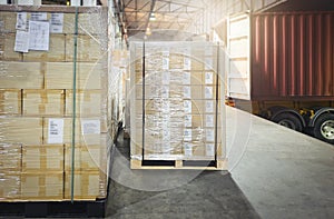 Package Boxes Wrapped Plastic Film on Pallets Loading with Shipping Cargo Container. Supply Chain. Trucks Parked Loading at Dock.