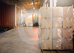 Package Boxes Wrapped Plastic Stacked on Pallets. Trailer Trucks Loading at Dock Warehouse.