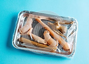 Package covered with food wrap with plastic dolls body parts. Concept of human trafficking and illegal organ trafficking.