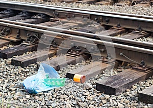 A package with garbage on the railway thrown out from the window of the train by passengers, pollution, debris and the railway