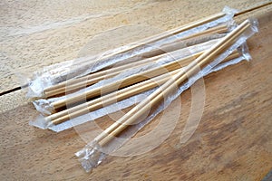 Package of readymade bamboo chopsticks on wooden background photo