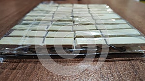 Package of wooden white clothespins on a brown wooden surface photo