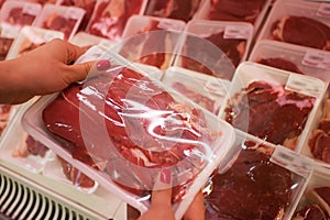 Packaged meat with woman hand in the supermarket