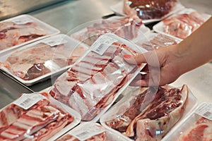 Packaged meat with woman hand in the supermarket