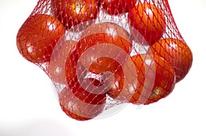 Packaged tomatoes hanging in red plastic net