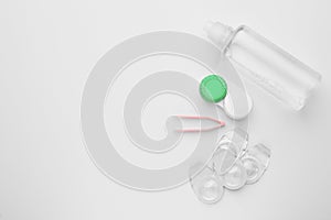 Packages with contact lenses, case, tweezers and drops on white background, flat lay. Space for text