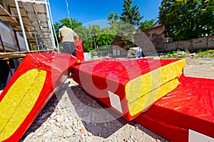 Packages with stone wool arranged in a pile, the workman is hanging the packet with stone wool on the crane hook