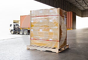 Packaging Boxes Wrapped Plastic on Pallets Loading into Shipping Cargo Container. Delivery Trucks Parked Loading at Dock Warehouse