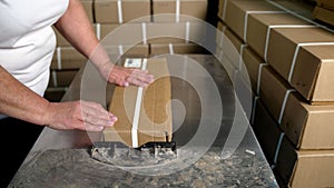 Packaging of goods. Close-up of a woman packing a cardboard box in a warehouse. Packaging goods in cardboard boxes