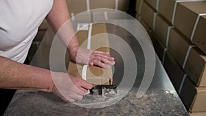 Packaging of goods. Close-up of a woman packing a cardboard box in a warehouse. Packaging goods in cardboard boxes