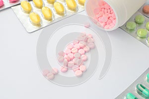 Packaging medicine tablet around open bottle of pink medicine table