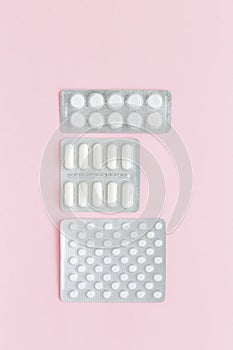 Packaging of white pills and capsules with medicine on pink background. Women Health. Disease prevention. Copy space.