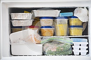 A packed freezer with soup and chicken