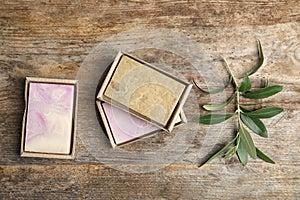 Packed handmade soap bars and olive twig on wooden table