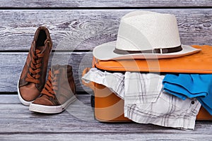 Packed suitcase, sneakers and straw hat.