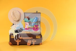 Packed vintage suitcase with different beach objects on background, space for text. Summer vacation