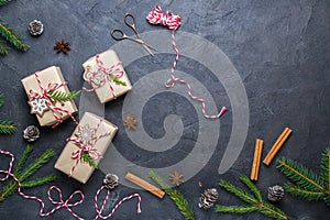 Packing Christmas gifts. Christmas gift boxes and decorations, pine branches on dark table. Present decorated with natural parts