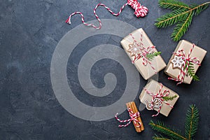 Packing Christmas gifts. Christmas gift boxes and decorations, pine branches on dark table. Present decorated with natural parts