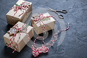 Packing Christmas gifts. Christmas gift boxes and decorations, pine branches on dark table. Present decorated with natural parts