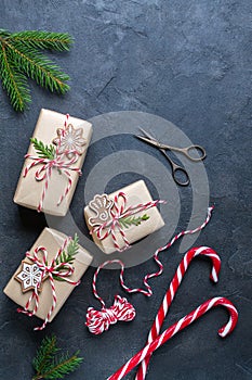 Packing Christmas gifts. Christmas gift boxes and decorations, pine branches on dark table. Present decorated with natural parts