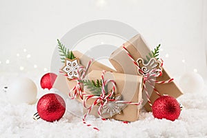 Packing Christmas gifts. Christmas gift boxes and decorations, pine branches on white snow background.