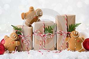 Packing Christmas gifts. Three Christmas gift boxes wrapped in kraft paper tied with red and white string , gingerbread men